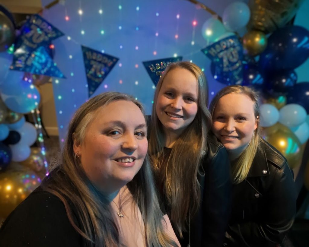Facepainter.com Team photo - Beccy, Charlotte and Jessica. With a balloon arch and light backdrop.